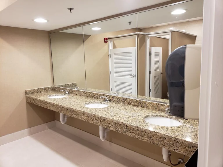 Renovated commercial restroom with tiled walls and a wall-mounted vanity